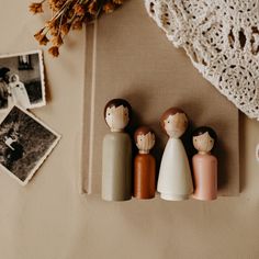 small wooden dolls sitting on top of a table next to an old lace doily