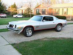 a silver and red car parked on the side of a road in front of a house