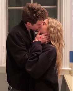 a man and woman kissing each other in front of a window with the words love on it