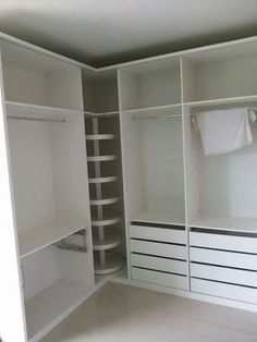 an empty walk in closet with white cabinets and drawers