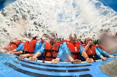 a group of men riding on the back of a raft down a wave machine in water