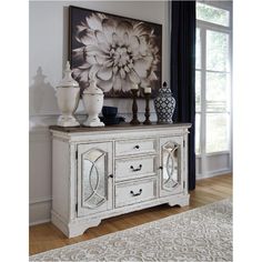 a white dresser sitting in front of a window next to a painting on the wall