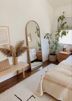 a bedroom with a bed, mirror and plants