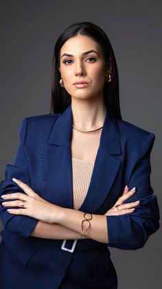 a woman in a blue suit posing with her arms crossed