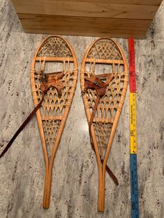 two wooden sleds sitting on top of a floor next to a measuring tape