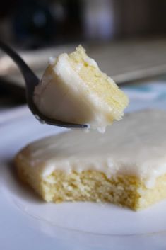 a piece of cake on a white plate with a fork in the foreground and a bite taken out of it