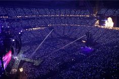 an aerial view of a concert venue at night with blue lights on the stage and people in the audience