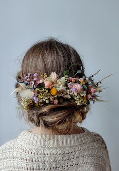 a woman with a flower crown on her head is looking down at the ground while wearing a sweater