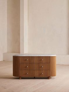 a wooden dresser sitting on top of a hard wood floor next to a white wall