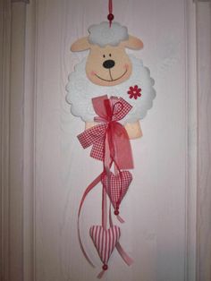 a door hanger with a sheep hanging from it's side and a red ribbon around the neck