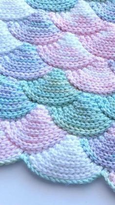 a crocheted blanket with pastel colors on the bottom and white, blue, green, pink, and purple circles