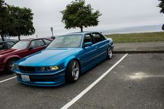 two cars parked in a parking lot next to each other near the water and trees