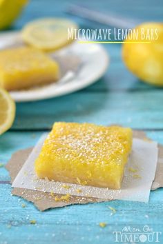 a lemon bar sitting on top of a piece of paper next to sliced lemons