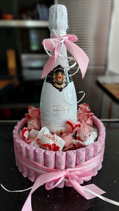 a bottle of champagne in a pink box with candy on the table next to it