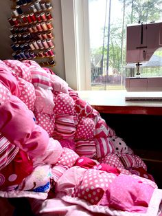 a pile of pink and white polka dot pillows next to a sewing machine on a table