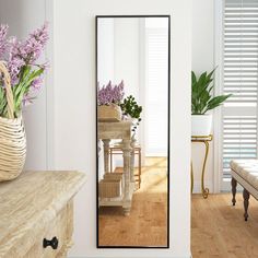 a mirror sitting on top of a wooden table next to a vase filled with flowers