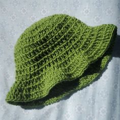 a green crocheted hat laying on top of a bed