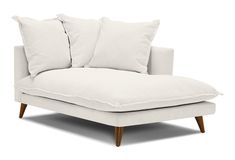 a white couch with two pillows on it's back and one arm folded down