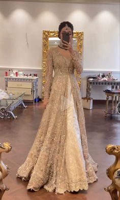 a woman taking a selfie in front of a mirror wearing a gown and holding a cell phone