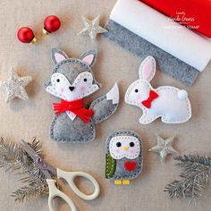 some felt animals are sitting on the table next to scissors and christmas decorations, including a santa's sleigh