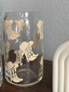 two glasses sitting next to each other on top of a wooden table with paper cutouts