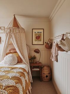a bedroom with a canopy bed next to a small table and baskets on the wall