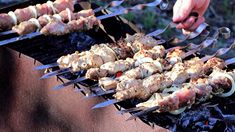 several skewered meats are being cooked on a bbq with tongs