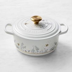 a white casserole with gold lid and flowers on it