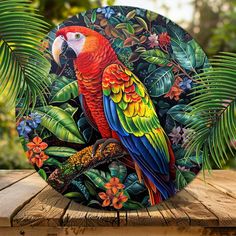 a colorful parrot sitting on top of a wooden table next to green leaves and flowers