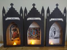 three small shrines with candles in front of them on top of a wooden table