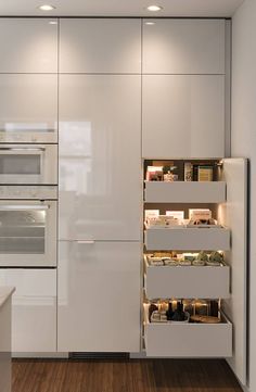 a kitchen with white cupboards and an oven in the center, along with wooden flooring