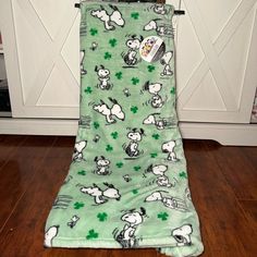 a green blanket with snoopy dogs and shamrocks on it sitting in front of a white door