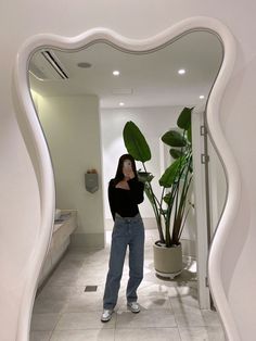 a woman taking a selfie in front of a mirror with a potted plant