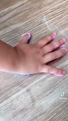 a handprint keychain is being held in someone's hand with pink and blue ink on it