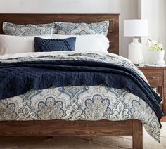 a bed with blue and white comforter in a bedroom next to two nightstands