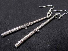 pair of silver toned earrings with dangling hooks on black fabric background, closeup