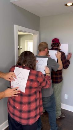 several people standing in a room with drawings on the wall and one person holding up a piece of paper