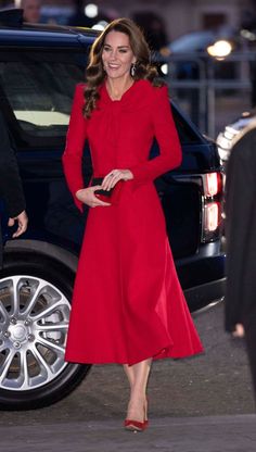 the duke and duchess of cambridge are seen in red outfits as they walk past an suv