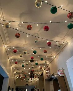 christmas lights are hanging from the ceiling in this hallway decorated with red, green and white ornaments