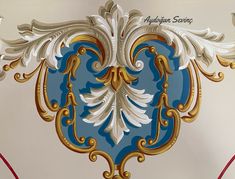 an ornate blue and gold wall hanging on the side of a white wall with red trim