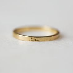 a yellow gold wedding band with the word graham engraved on it's side, sitting on a white surface