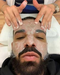 a man is shaving his face while getting facial care from a woman's hands