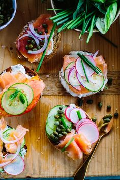 a wooden cutting board topped with sandwiches and veggies