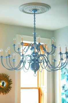 a chandelier hanging from the ceiling in a room with windows and a mirror