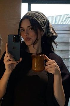 a woman taking a selfie while holding a coffee mug