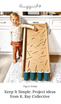 a little boy standing in front of a cardboard box with sticks sticking out of it