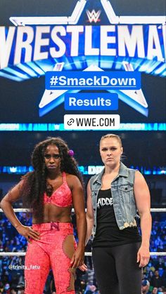two women standing next to each other in front of a wrestling match sign with the wwe logo