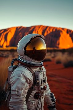 an astronaut is standing in front of a mountain with his helmet on and looking at the camera