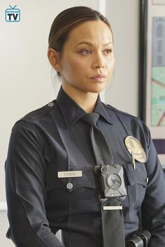 a female police officer is standing in front of the camera and looking at the camera