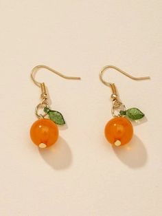 two oranges with leaves on them are hanging from gold earwires and earrings